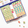 Open children's mahjong set with tiles and dice on a white background