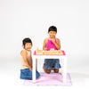 Two young girls playing Mahjong with wooden blocks on a small table against a white background