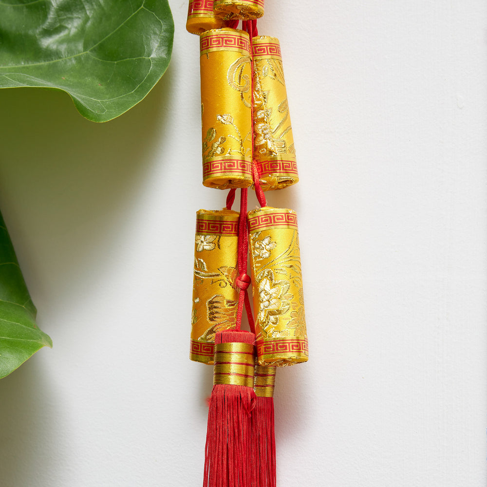 Firecracker hanging made of silken fabric, gold with red details, and Chinese knot and tassel. 