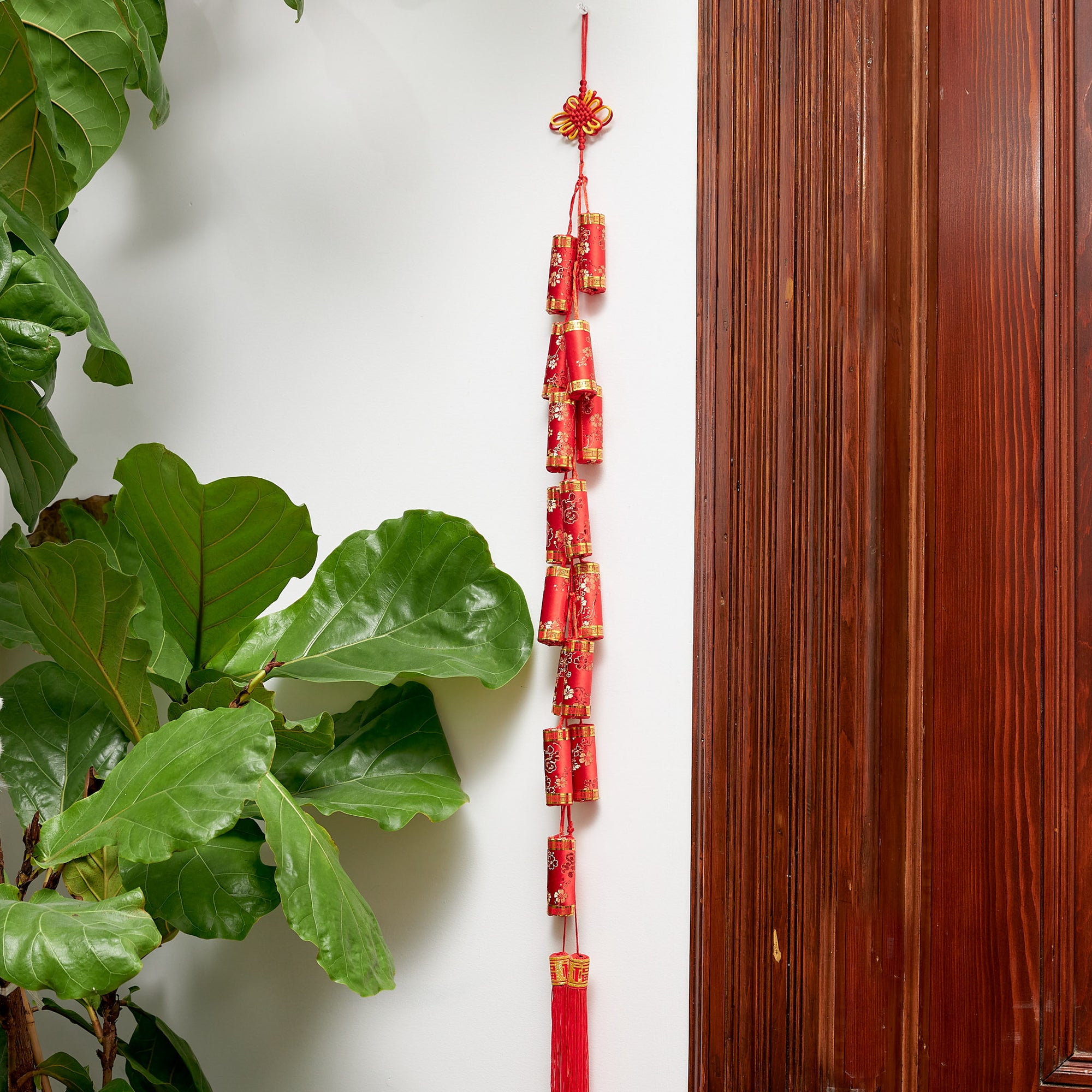 Firecracker hanging made of silken fabric, red with gold details, and Chinese knot and tassel. 