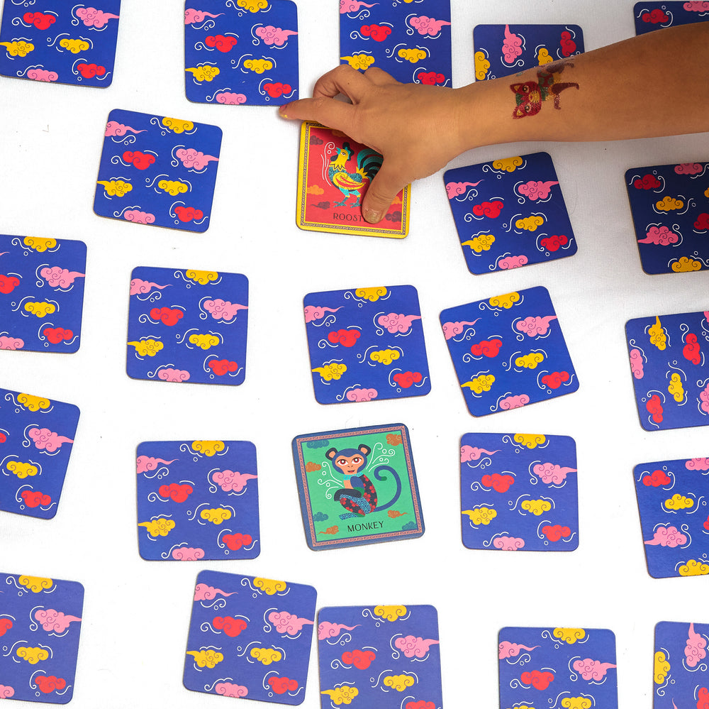 Colorful card game with chinese zodiac animals, hand reaching for a card.