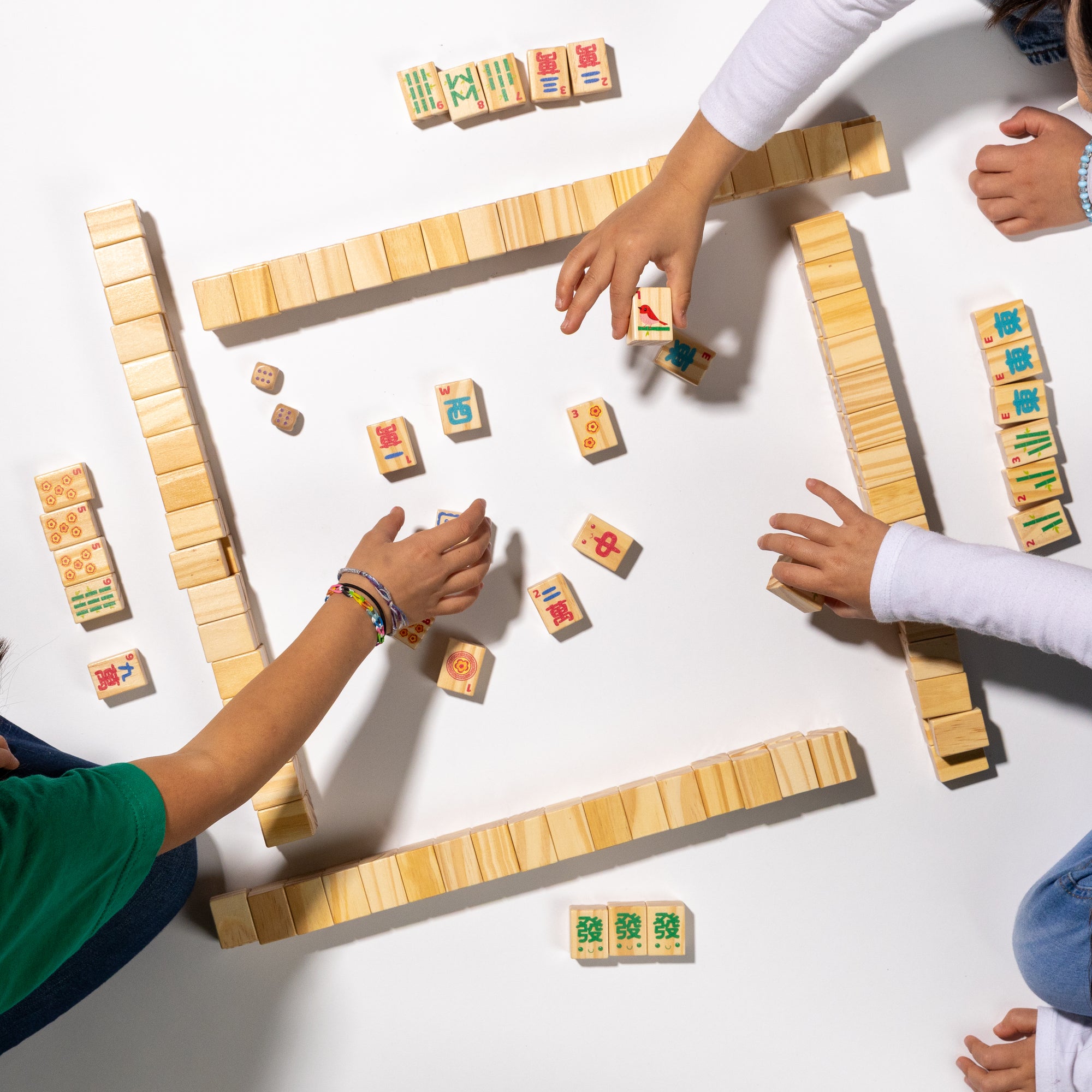 Children playing with wooden mahjong on a white surface